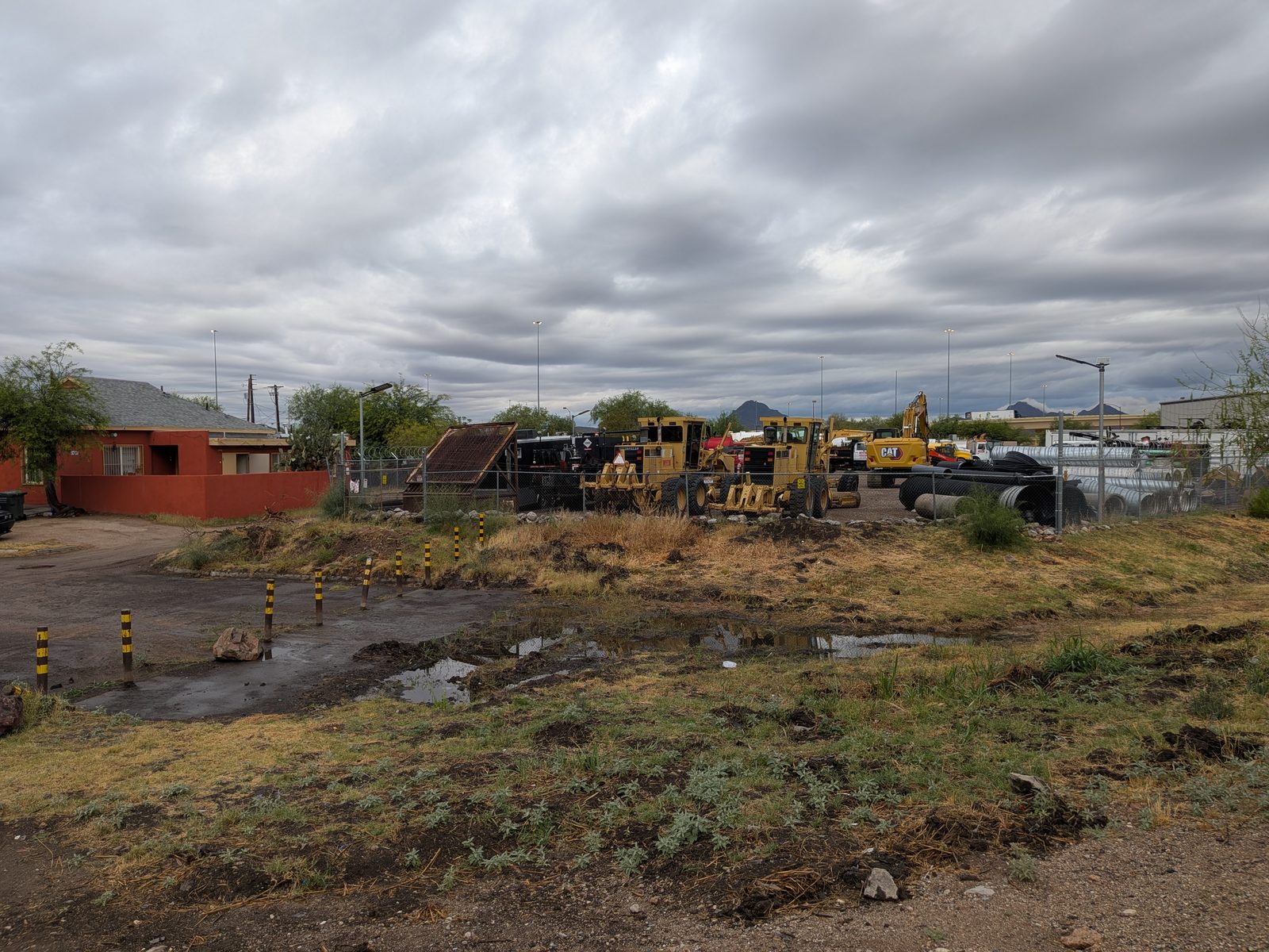 Wider angle showing residential houses on the left adjacent to the Magnum Paving contractor's yard with heavy equipment.